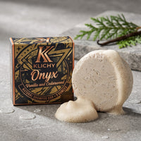 Onyx cedarwood and vanilla shampoo bar lathering into rich creamy foam on wet stone