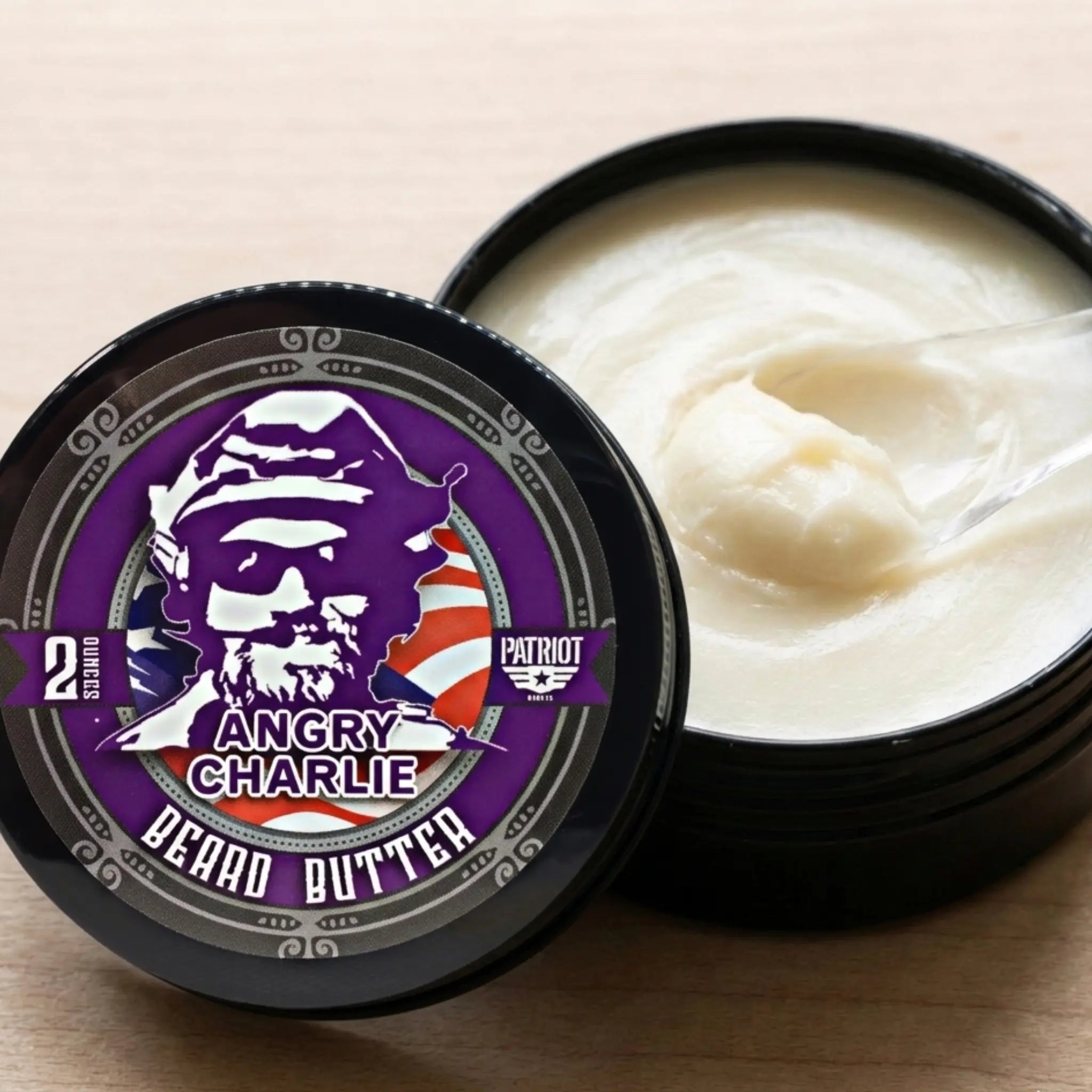 Close-up of an open tin of Flagship Soap Company’s Angry Charlie beard butter, showing the smooth, creamy whipped texture of the vanilla and cedarwood scented balm.