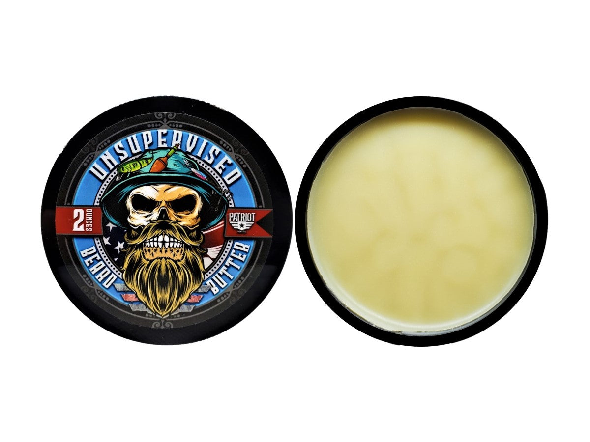 Top-down view of Unsupervised Beard Butter showing the patriotic fisherman skull lid design next to the open tin of product. The beard butter has a smooth, creamy consistency, highlighting the natural grooming ingredients.
